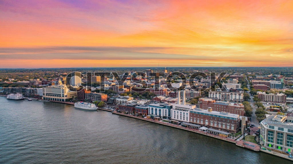 Aerial view of Savannah, GA showing riverfront and cityscape at sunset